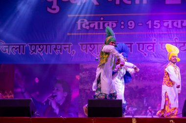 Puşkar, Rajasthan, Hindistan - 11 Kasım 2024: Bhangra, Bhangra grubu, açık hava kültür gecesi renkli etnik elbiseler içinde bhangra dansı yapıyor.