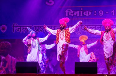 Puşkar, Rajasthan, Hindistan - 11 Kasım 2024: Bhangra, Bhangra grubu, açık hava kültür gecesi renkli etnik elbiseler içinde bhangra dansı yapıyor.