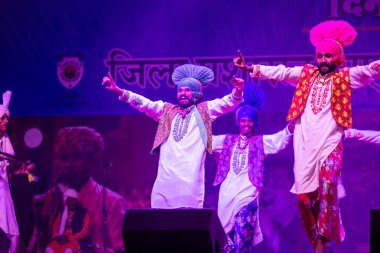 Puşkar, Rajasthan, Hindistan - 11 Kasım 2024: Bhangra, Bhangra grubu, açık hava kültür gecesi renkli etnik elbiseler içinde bhangra dansı yapıyor.
