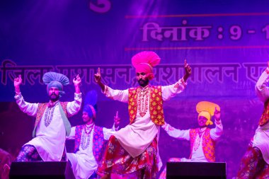 Puşkar, Rajasthan, Hindistan - 11 Kasım 2024: Bhangra, Bhangra grubu, açık hava kültür gecesi renkli etnik elbiseler içinde bhangra dansı yapıyor.