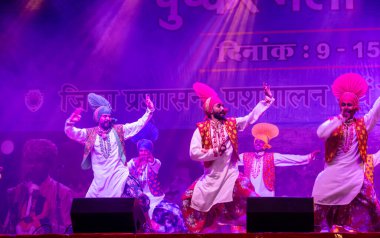 Puşkar, Rajasthan, Hindistan - 11 Kasım 2024: Bhangra, Bhangra grubu, açık hava kültür gecesi renkli etnik elbiseler içinde bhangra dansı yapıyor.