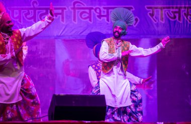 Puşkar, Rajasthan, Hindistan - 11 Kasım 2024: Bhangra, Bhangra grubu, açık hava kültür gecesi renkli etnik elbiseler içinde bhangra dansı yapıyor.