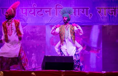 Puşkar, Rajasthan, Hindistan - 11 Kasım 2024: Bhangra, Bhangra grubu, açık hava kültür gecesi renkli etnik elbiseler içinde bhangra dansı yapıyor.