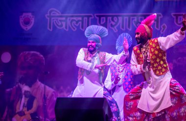 Puşkar, Rajasthan, Hindistan - 11 Kasım 2024: Bhangra, Bhangra grubu, açık hava kültür gecesi renkli etnik elbiseler içinde bhangra dansı yapıyor.