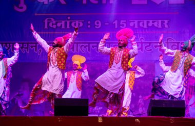 Puşkar, Rajasthan, Hindistan - 11 Kasım 2024: Bhangra, Bhangra grubu, açık hava kültür gecesi renkli etnik elbiseler içinde bhangra dansı yapıyor.