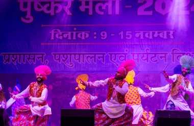 Puşkar, Rajasthan, Hindistan - 11 Kasım 2024: Bhangra, Bhangra grubu, açık hava kültür gecesi renkli etnik elbiseler içinde bhangra dansı yapıyor.