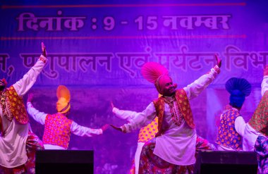 Puşkar, Rajasthan, Hindistan - 11 Kasım 2024: Bhangra, Bhangra grubu, açık hava kültür gecesi renkli etnik elbiseler içinde bhangra dansı yapıyor.