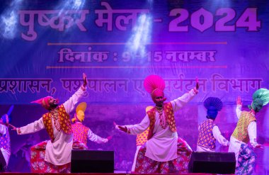 Puşkar, Rajasthan, Hindistan - 11 Kasım 2024: Bhangra, Bhangra grubu, açık hava kültür gecesi renkli etnik elbiseler içinde bhangra dansı yapıyor.