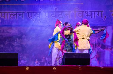 Puşkar, Rajasthan, Hindistan - 11 Kasım 2024: Halk dansı, Hintli erkek ve kadın sanatçılardan oluşan bir grup, Chhattisgarh eyaletinin rengarenk etnik kıyafetleriyle sokak dansı yapıyorlar.