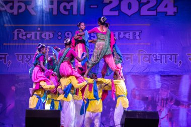 Puşkar, Rajasthan, Hindistan - 11 Kasım 2024: Halk dansı, Hintli erkek ve kadın sanatçılardan oluşan bir grup, Chhattisgarh eyaletinin rengarenk etnik kıyafetleriyle sokak dansı yapıyorlar.