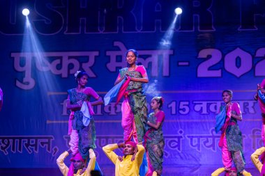Puşkar, Rajasthan, Hindistan - 11 Kasım 2024: Halk dansı, Hintli erkek ve kadın sanatçılardan oluşan bir grup, Chhattisgarh eyaletinin rengarenk etnik kıyafetleriyle sokak dansı yapıyorlar.
