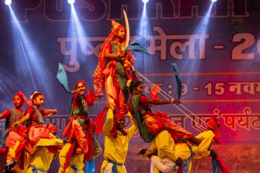 Puşkar, Rajasthan, Hindistan - 11 Kasım 2024: Halk dansı, Hintli erkek ve kadın sanatçılardan oluşan bir grup, Chhattisgarh eyaletinin rengarenk etnik kıyafetleriyle sokak dansı yapıyorlar.