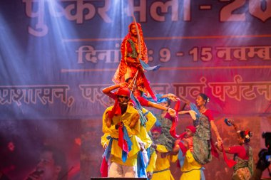 Puşkar, Rajasthan, Hindistan - 11 Kasım 2024: Halk dansı, Hintli erkek ve kadın sanatçılardan oluşan bir grup, Chhattisgarh eyaletinin rengarenk etnik kıyafetleriyle sokak dansı yapıyorlar.