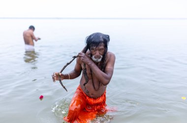 Varanasi, Hindistan - 15 Aralık 2024: Ganj nehrinde bir adam ve bir rahip. Varanasi 'de.