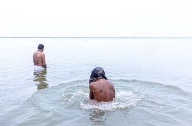 Varanasi, Hindistan - 15 Aralık 2024: Ganj nehrinde bir adam ve bir rahip. Varanasi 'de.