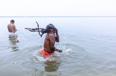 Varanasi, Hindistan - 15 Aralık 2024: Ganj nehrinde bir adam ve bir rahip. Varanasi 'de.
