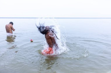 Varanasi, Hindistan - 15 Aralık 2024: Ganj nehrinde bir adam ve bir rahip. Varanasi 'de.