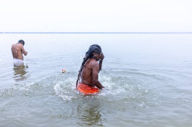 Varanasi, Hindistan - 15 Aralık 2024: Ganj nehrinde bir adam ve bir rahip. Varanasi 'de.