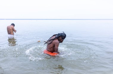 Varanasi, Hindistan - 15 Aralık 2024: Ganj nehrinde bir adam ve bir rahip. Varanasi 'de.