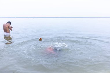 Varanasi, Hindistan - 15 Aralık 2024: Ganj nehrinde bir adam ve bir rahip. Varanasi 'de.