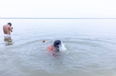Varanasi, Hindistan - 15 Aralık 2024: Ganj nehrinde bir adam ve bir rahip. Varanasi 'de.