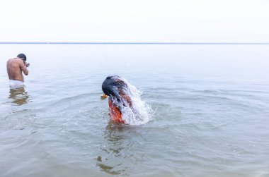 Varanasi, Hindistan - 15 Aralık 2024: Ganj nehrinde bir adam ve bir rahip. Varanasi 'de.