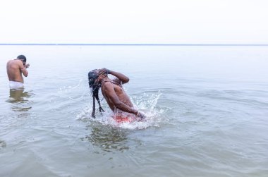 Varanasi, Hindistan - 15 Aralık 2024: Ganj nehrinde bir adam ve bir rahip. Varanasi 'de.