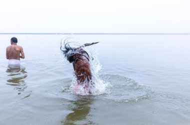 Varanasi, Hindistan - 15 Aralık 2024: Ganj nehrinde bir adam ve bir rahip. Varanasi 'de.