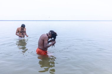 Varanasi, Hindistan - 15 Aralık 2024: Ganj nehrinde bir adam ve bir rahip. Varanasi 'de.