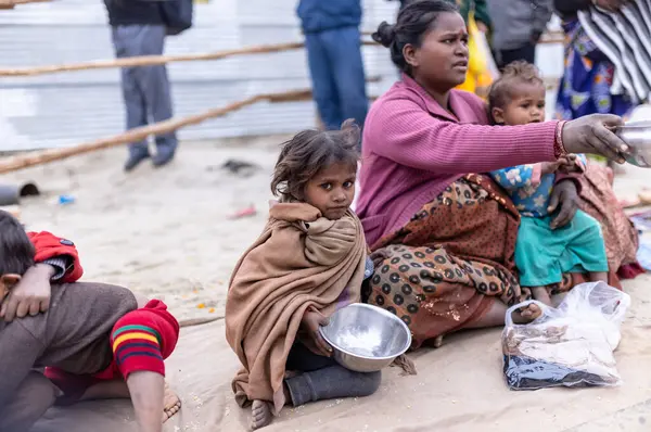 Prayagraj, Uttar Pradesh, Hindistan - 14 Ocak 2025: Mahakumbh, Paşagraj 'daki maha kumbh mela sırasında aileleriyle yol kenarında oturan bir grup çocuk.
