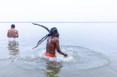 Varanasi, Hindistan - 15 Aralık 2024: Ganj nehrinde bir adam ve bir rahip. Varanasi 'de.