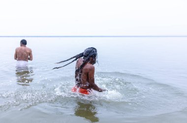 Varanasi, Hindistan - 15 Aralık 2024: Ganj nehrinde bir adam ve bir rahip. Varanasi 'de.