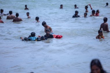 Kulashekharapatnam, Tamilnadu, Hindistan - 12 Ekim 2024: Kulasai Dasara, bir grup çocuk ve ebeveynleri kulasai dasara festivalinde deniz dalgalarının keyfini çıkarıyorlar.