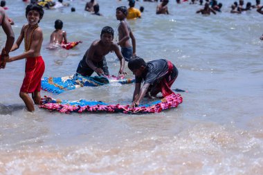 Kulashekharapatnam, Tamilnadu, Hindistan - 12 Ekim 2024: Kulasai Dasara, bir grup çocuk ve ebeveynleri kulasai dasara festivalinde deniz dalgalarının keyfini çıkarıyorlar.