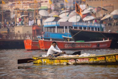 Varanasi, Uttar Pradesh, Hindistan - 20 Ocak 2024: Turistler sabahın erken saatlerinde Varanasi 'deki nehir çetelerinde tekne turunun keyfini çıkarıyorlar. Kayıkçı kışın sisli sabahında tahta teknede yelken açıyor..