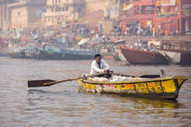 Varanasi, Uttar Pradesh, Hindistan - 20 Ocak 2024: Turistler sabahın erken saatlerinde Varanasi 'deki nehir çetelerinde tekne turunun keyfini çıkarıyorlar. Kayıkçı kışın sisli sabahında tahta teknede yelken açıyor..