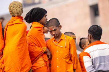 Varanasi, Uttar Pradesh, Hindistan - 20 Ocak 2024: Gurukul 'un ya da okulun kimliği belirsiz erkek öğrencileri kış sabahı Varanasi' de kutsal nehir keneviri yakınlarındaki ghat üzerinde oturuyorlar.