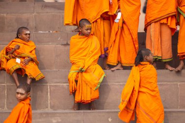 Varanasi, Uttar Pradesh, Hindistan - 20 Ocak 2024: Gurukul 'un ya da okulun kimliği belirsiz erkek öğrencileri kış sabahı Varanasi' de kutsal nehir keneviri yakınlarındaki ghat üzerinde oturuyorlar.