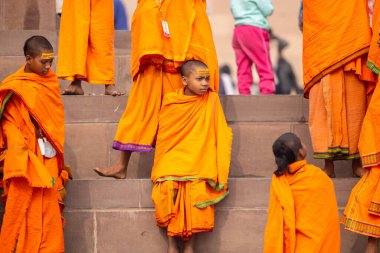 Varanasi, Uttar Pradesh, Hindistan - 20 Ocak 2024: Gurukul 'un ya da okulun kimliği belirsiz erkek öğrencileri kış sabahı Varanasi' de kutsal nehir keneviri yakınlarındaki ghat üzerinde oturuyorlar.