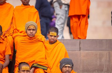 Varanasi, Uttar Pradesh, Hindistan - 20 Ocak 2024: Gurukul 'un ya da okulun kimliği belirsiz erkek öğrencileri kış sabahı Varanasi' de kutsal nehir keneviri yakınlarındaki ghat üzerinde oturuyorlar.