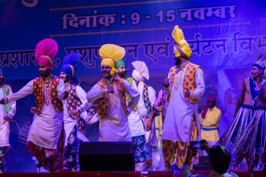 Puşkar, Rajasthan, Hindistan - 11 Kasım 2024: Bhangra, Bhangra grubu, açık hava kültür gecesi renkli etnik elbiseler içinde bhangra dansı yapıyor.