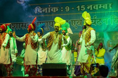 Puşkar, Rajasthan, Hindistan - 11 Kasım 2024: Bhangra, Bhangra grubu, açık hava kültür gecesi renkli etnik elbiseler içinde bhangra dansı yapıyor.