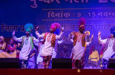 Puşkar, Rajasthan, Hindistan - 11 Kasım 2024: Bhangra, Bhangra Sanatçılar Grubu, renkli etnik elbiseler içinde dans ediyorlar..