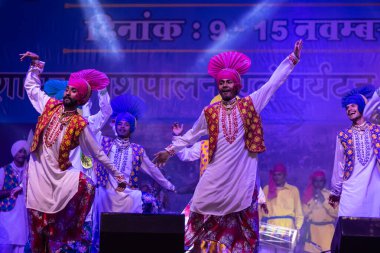 Puşkar, Rajasthan, Hindistan - 11 Kasım 2024: Bhangra, Bhangra Sanatçılar Grubu, renkli etnik elbiseler içinde dans ediyorlar..