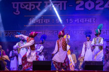 Puşkar, Rajasthan, Hindistan - 11 Kasım 2024: Bhangra, Bhangra Sanatçılar Grubu, renkli etnik elbiseler içinde dans ediyorlar..