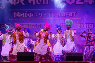 Puşkar, Rajasthan, Hindistan - 11 Kasım 2024: Bhangra, Bhangra Sanatçılar Grubu, renkli etnik elbiseler içinde dans ediyorlar..
