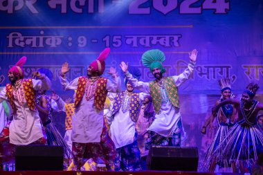Puşkar, Rajasthan, Hindistan - 11 Kasım 2024: Bhangra, Bhangra Sanatçılar Grubu, renkli etnik elbiseler içinde dans ediyorlar..