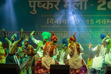 Puşkar, Rajasthan, Hindistan - 11 Kasım 2024: Bhangra, Bhangra Sanatçılar Grubu, renkli etnik elbiseler içinde dans ediyorlar..