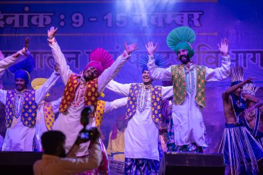 Puşkar, Rajasthan, Hindistan - 11 Kasım 2024: Bhangra, Bhangra Sanatçılar Grubu, renkli etnik elbiseler içinde dans ediyorlar..