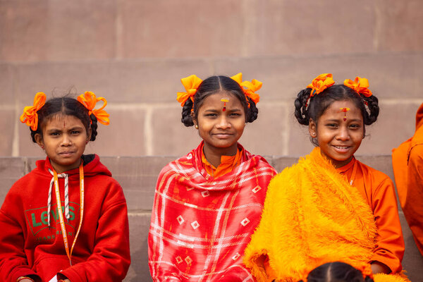 Varanasi, Uttar Pradesh, India - January 20 2024: Group of young unidentified female students of gurukul or school sitting at steps on ghats near holy river ganga in varanasi during winter morning.